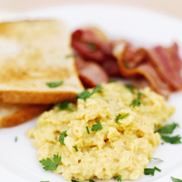 Close-up of scrambled eggs served with toast and bacon (blurred)