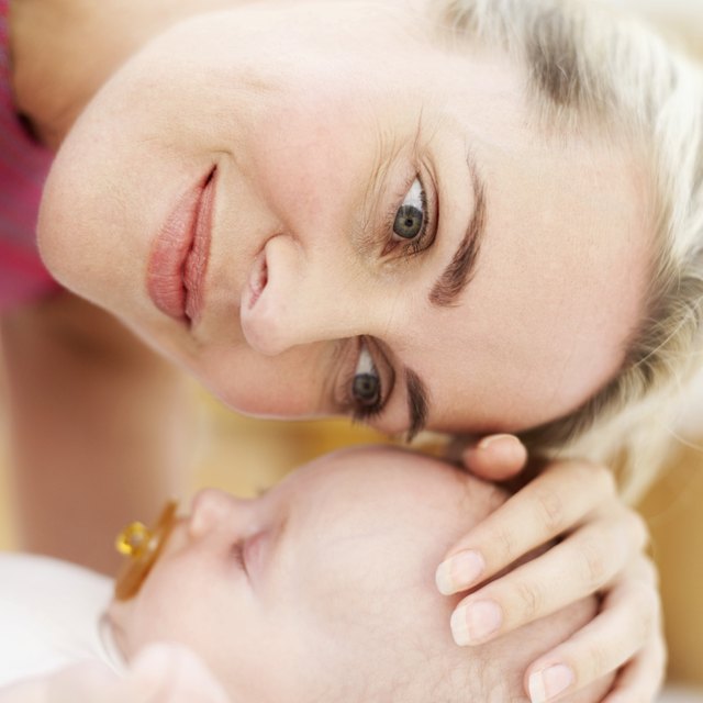 Close-up of a woman touching the top of a baby's head (3-6 months)
