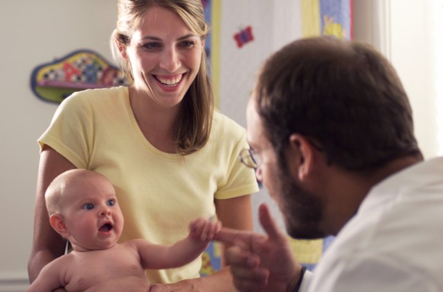 a young caucasian mother has her baby examined and admired by a male pediatricain