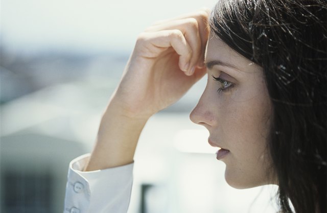 Young woman with hand on forehead outdoors,close-up,profile