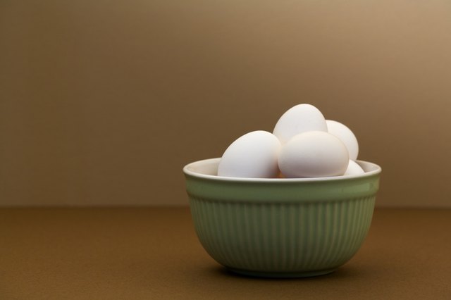 White eggs in green bowl on brown table