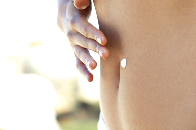 Woman applying cream on her belly