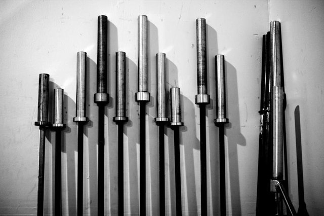 Weight lifting barbells leaning against a wall taken in black and white.