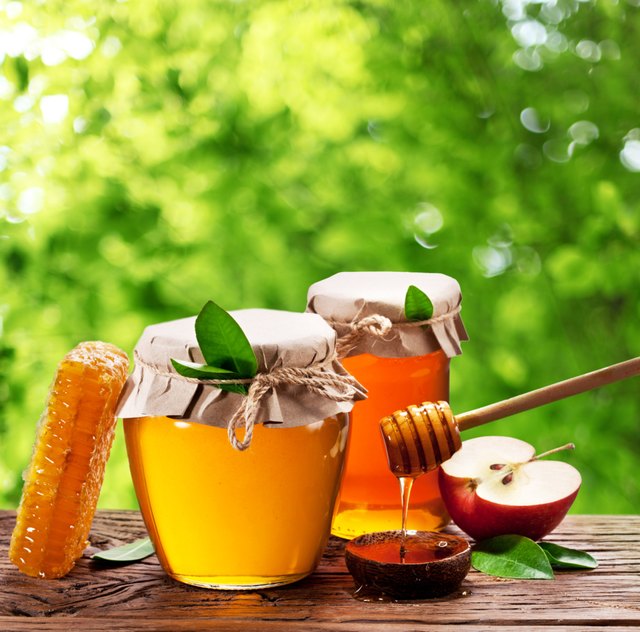 Glass cans full of honey, apples and combs.