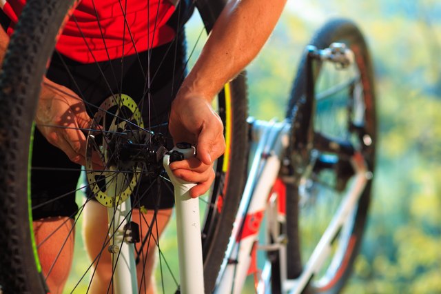 Man cyclist repairing a bike against blue sky