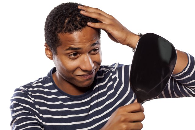 Dark-skinned young man settles himself in the mirror
