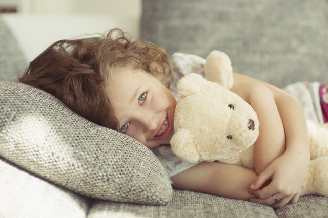 Young girl embracing teddy bear on sofa