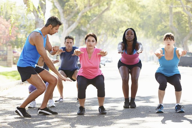 Group Of People Exercising Street With Personal Trainer