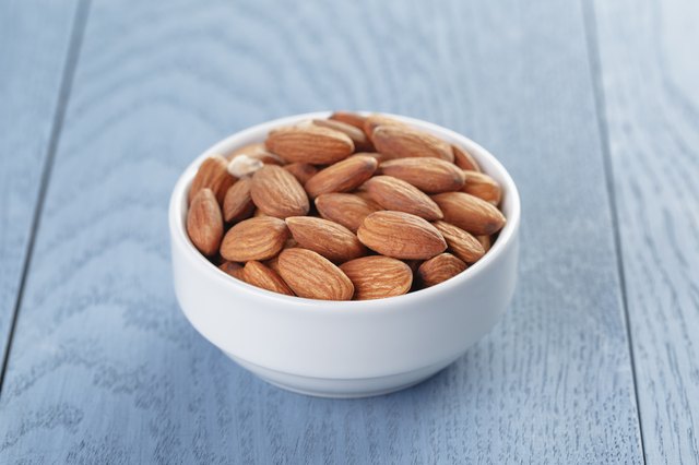 roasted almonds in white bowl on wooden table