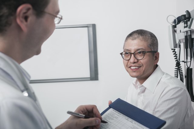 Doctor writing on medical chart with a smiling patient