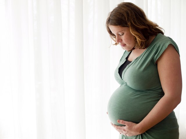 Pregnant young woman looking at her belly