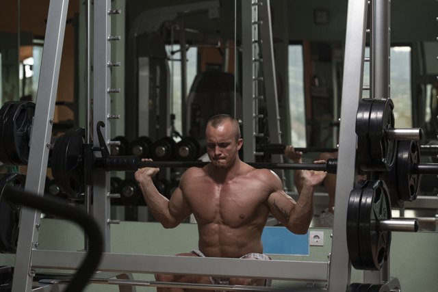 Young Man Performing Barbell Squats Exercise For Legs