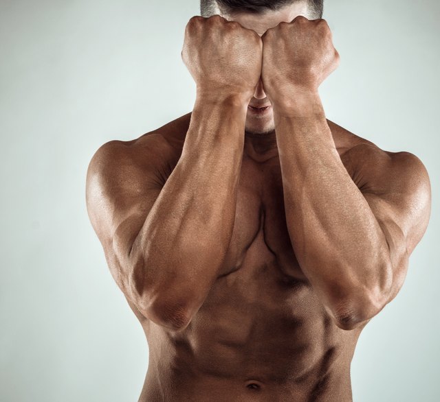 Two Power Mans Hands in Front of Face. Close-up of a man's fists and abs. Strong man's arm with muscles and veins.