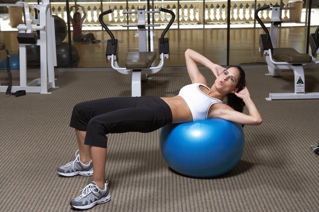 Woman doing exercise on fitness ball in gym, side view
