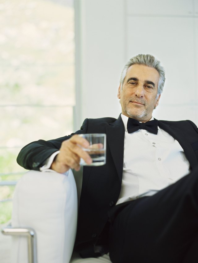Portrait of a mature man in a tuxedo holding a glass of water