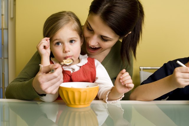 Woman feeding girl cereal