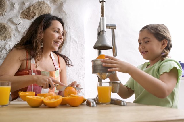 Mother and daughter squeezing oranges for juice