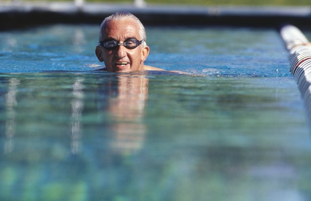 Senior man swimming in outdoor pool, surface view