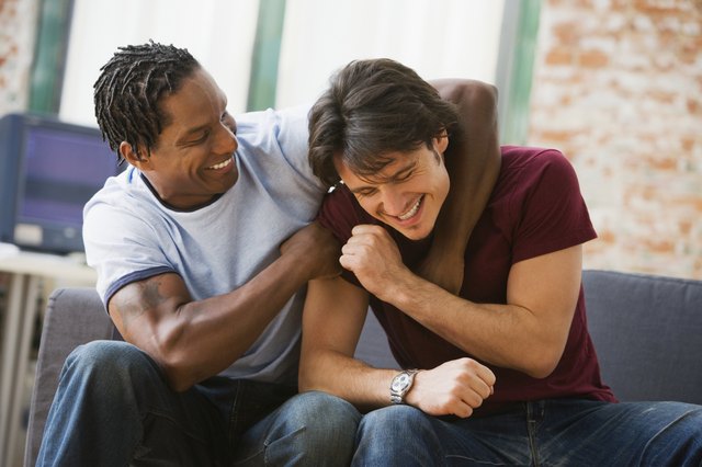 Multi-ethnic men hugging on sofa