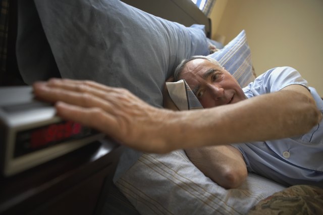 Close-up of a senior man touching an alarm clock