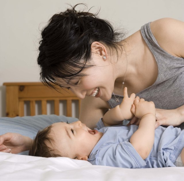 Mother playing with son on bed