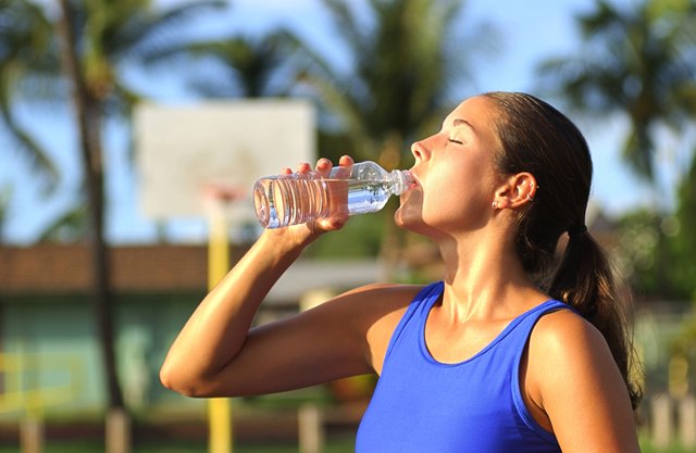 A close-up, side view of a teen Caucasian woman drinking bottled water