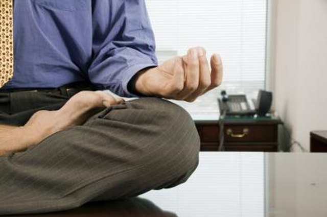 Businessman meditating barefoot on desk