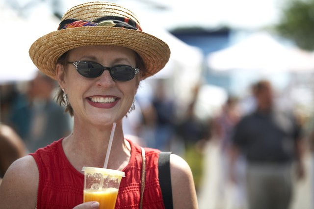 Close-up of a mature woman holding a glass of orange juice and smiling