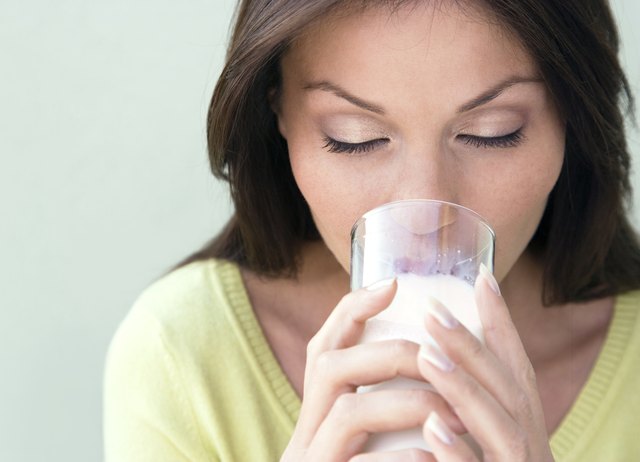 Young woman drinking milk, smiling, close-up