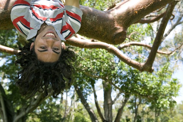 Portrait of a young man hanging upside down in a tree