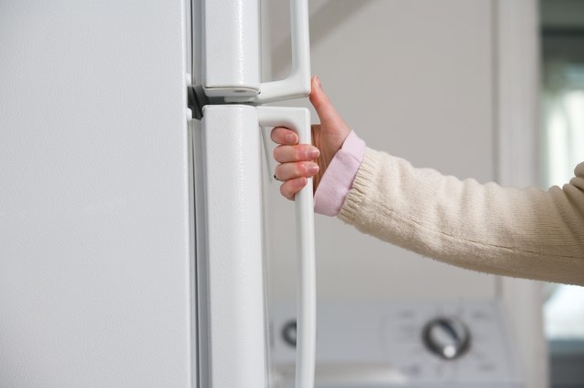 Hand of woman opening refrigerator door