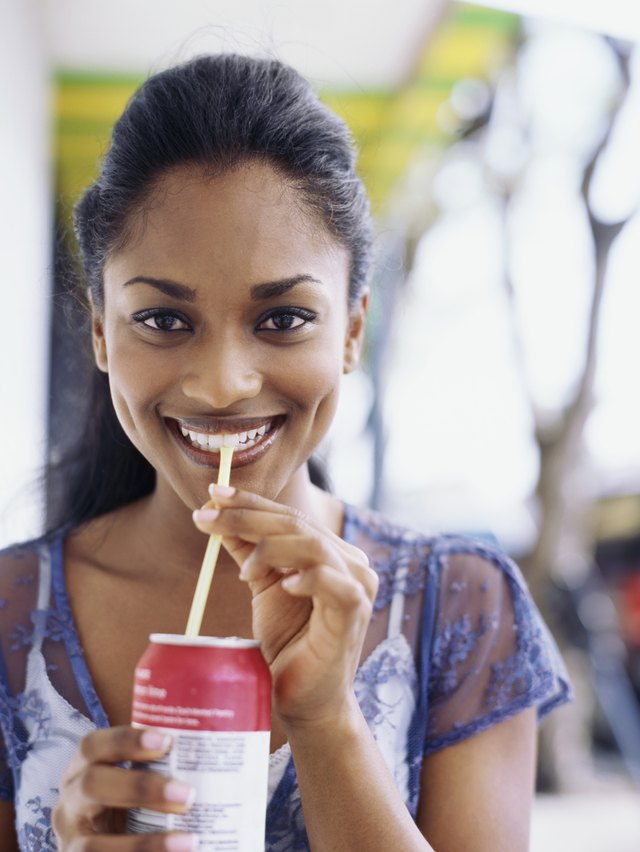 Portrait of a young woman drinking soda through a straw