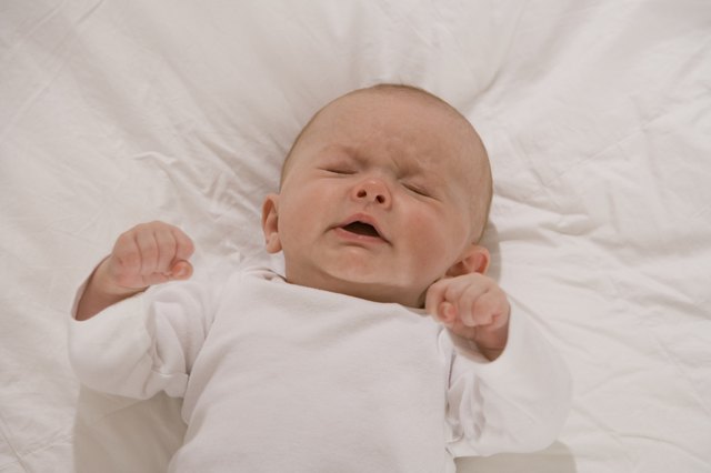 Unhappy baby lying down with eyes closed