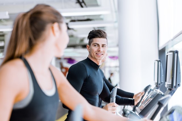 Handsome man and woman using a stepper in a gym