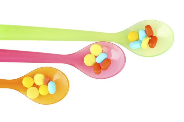Plastic spoons with color pills, isolated on white
