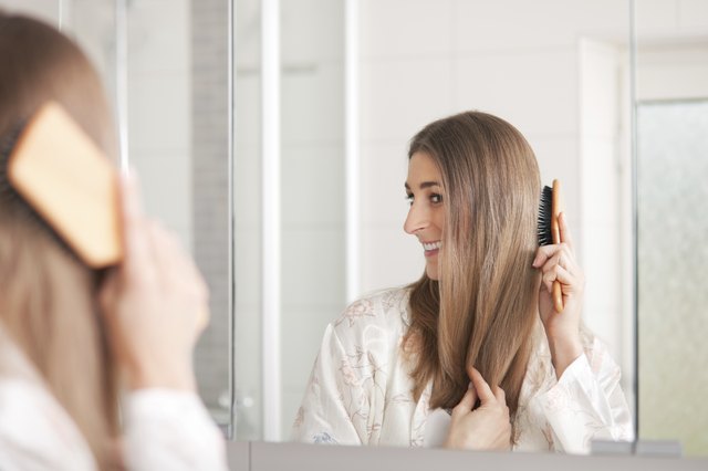 Young woman brushing her hair in front of the mirror