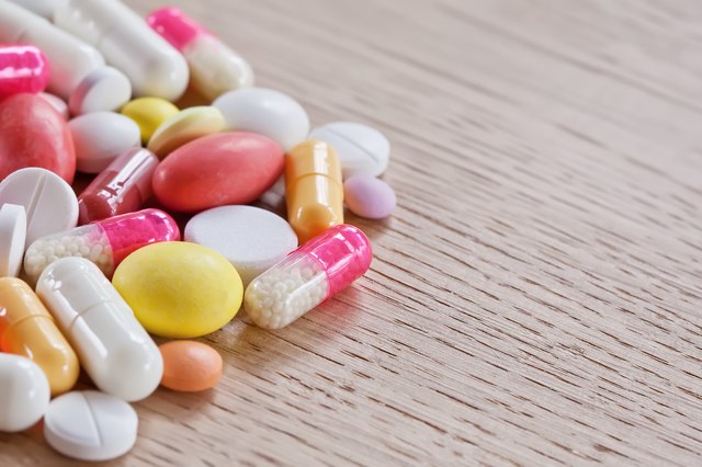 Multicoloured pills and capsules on the wooden surface