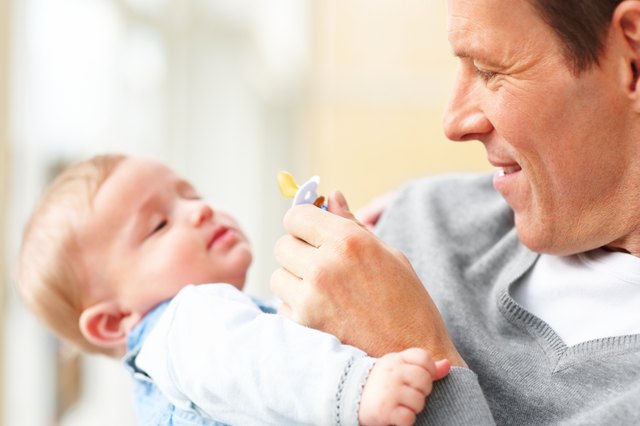 Closeup of a young father carrying his baby and holding a pacifi