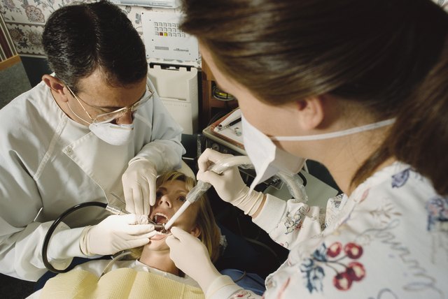 a dentist and his assistant work on a patient