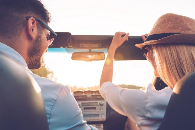 Rear view of joyful young couple having fun while riding in their convertible