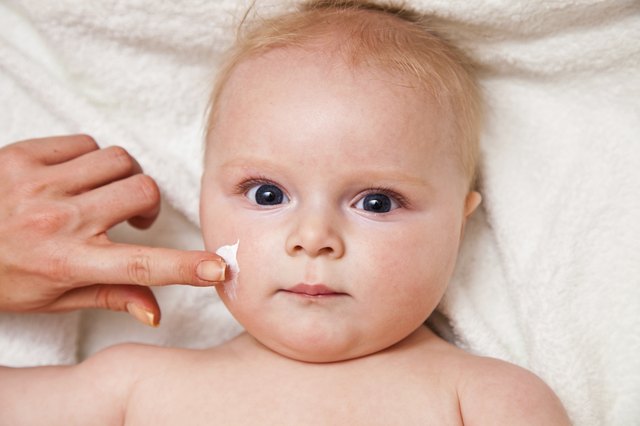 Creaming face of infant girl after bath
