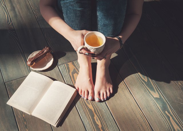 Cozy photo of young woman with tea and book