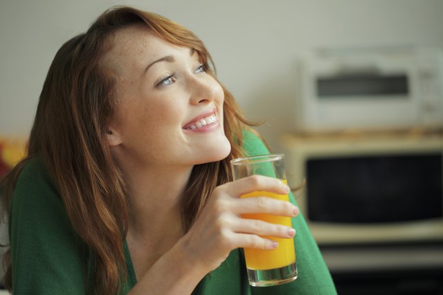 Young woman holding glass of orange juice and smiling