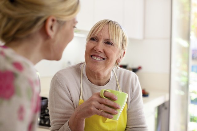 Mother and daughter talking, drinking coffee in kitchen