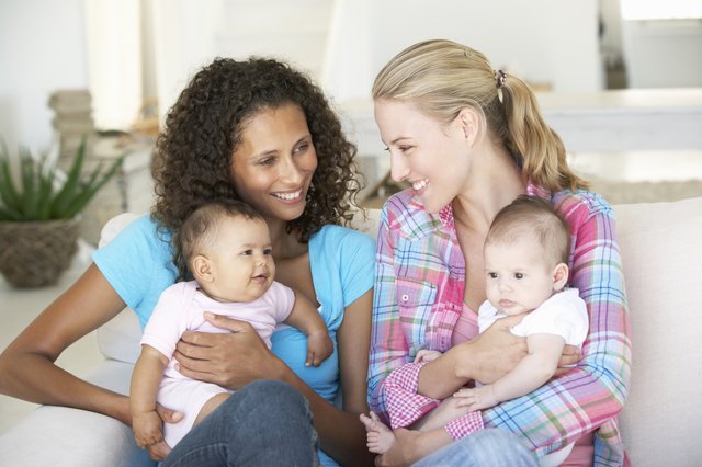 Two Young Mothers With Babies On Sofa At Home
