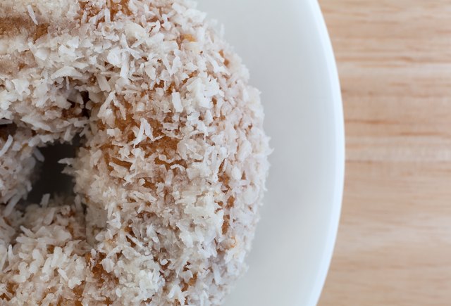 Top close view of coconut flake donut on white plate