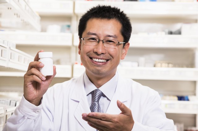 Portrait of smiling pharmacist holding a prescription medication bottle in his hand