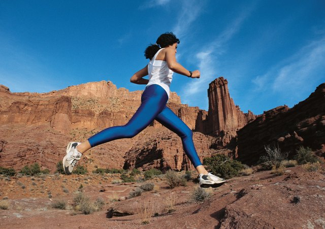 woman running across the desert in a blue spandex outfit at Fisher Towers in Moab Utah