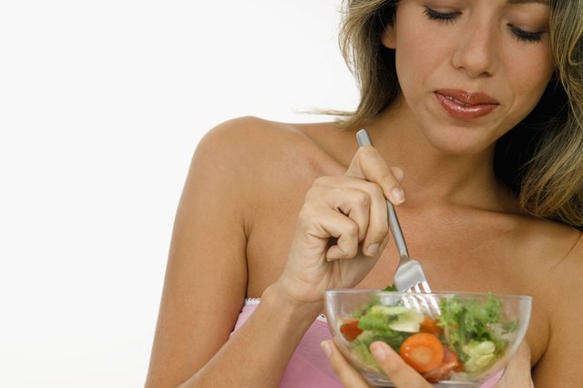 Young woman holding a fork in a bowl of salad