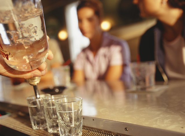 Barman pouring three shorts, close up of drinks